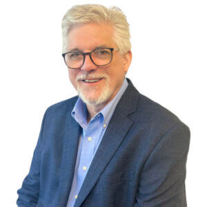 Gene is wearing a navy suit jacket over a blue button-up shirt