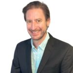 Matt is smiling and has short brown hair and wears a jacket