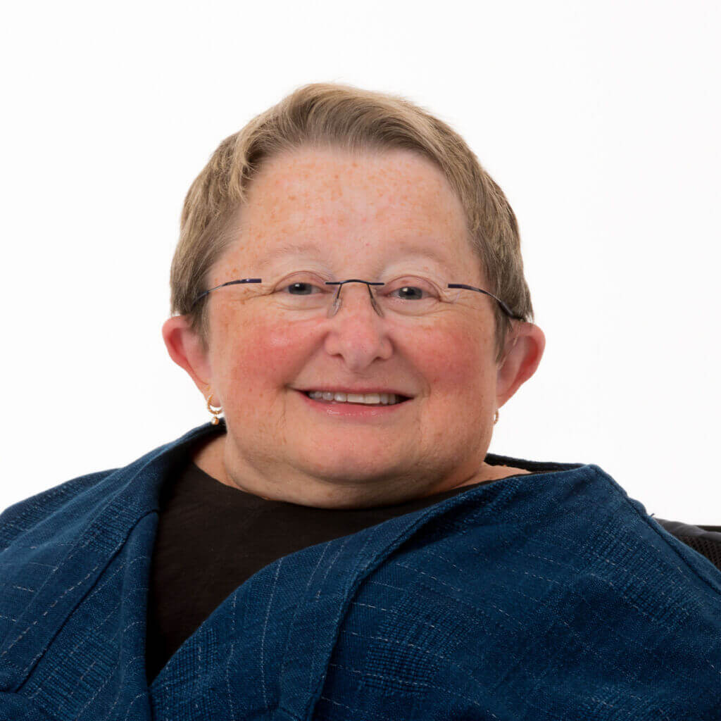 KarenB_Studio_Pacifica_9_22_123_DSheehan Karen has short blond hair, is wearing a black shirt under a navy jacket, and is smiling warmly at the camera