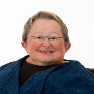 KarenB_Studio_Pacifica_9_22_123_DSheehan Karen has short blond hair, is wearing a black shirt under a navy jacket, and is smiling warmly at the camera