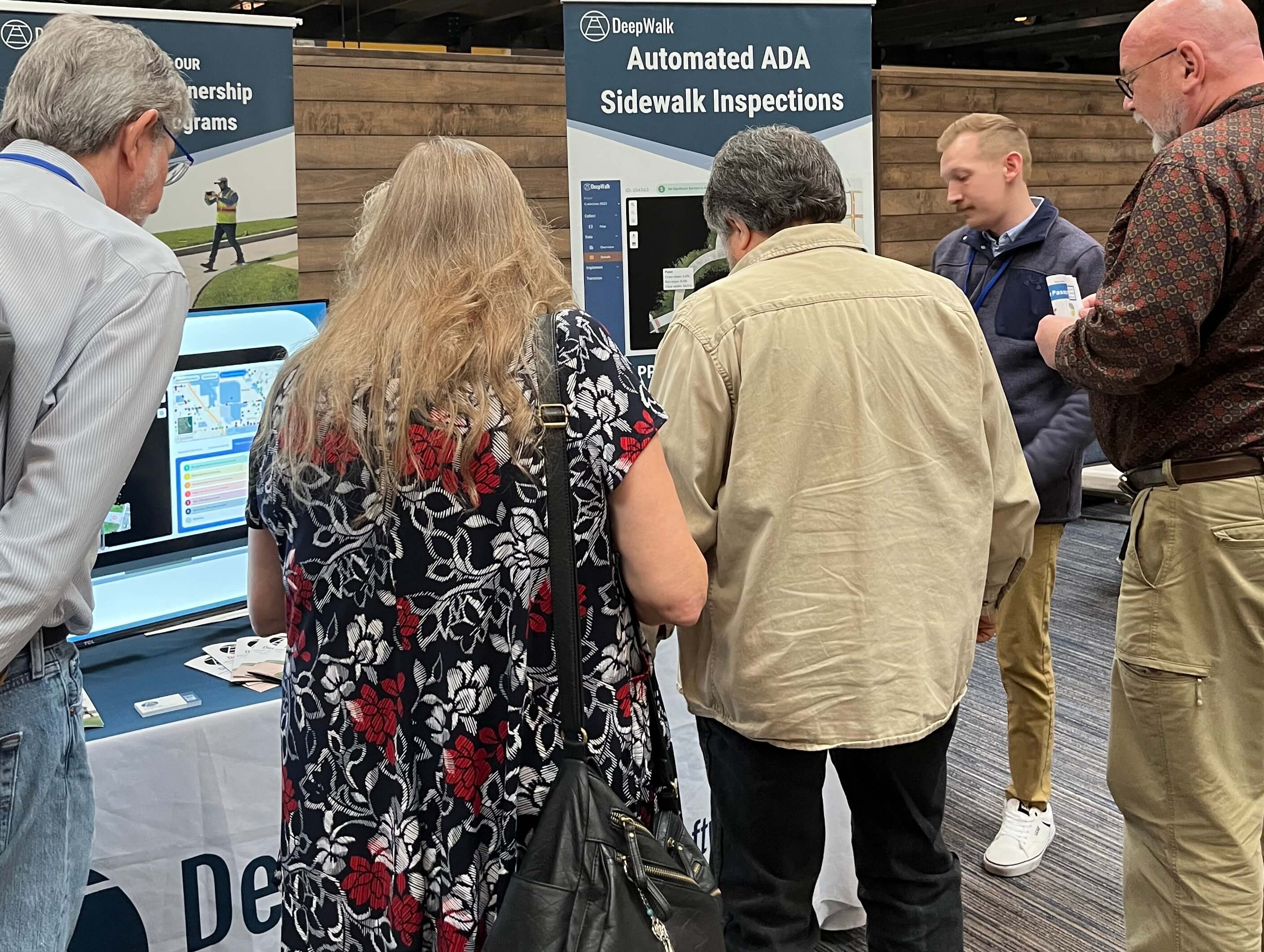 2025 Conference Exhibitor Photo A group of conference attendees standing around an exhibitor table talking to the booth representative