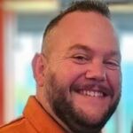 Jonathan is wearing a burnt orange polo shirt