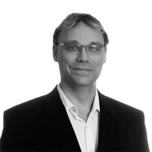 Monochromatic photo of Joshua wearing a dark suit jacket over a light button-up shirt