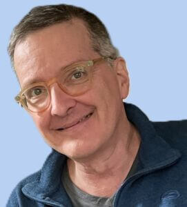 Jim is wearing a blue zippered fleece over a gray tshirt