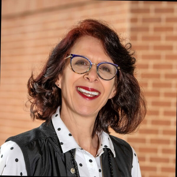 Kim Hooker Photo Kim is standing in front of a brick wall