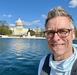 Michael is standing in front of the reflecting pool in front of the US Capital building