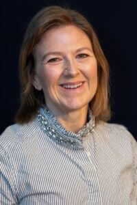 Meghan is wearing a striped buttoned shirt with jewels around the collar.