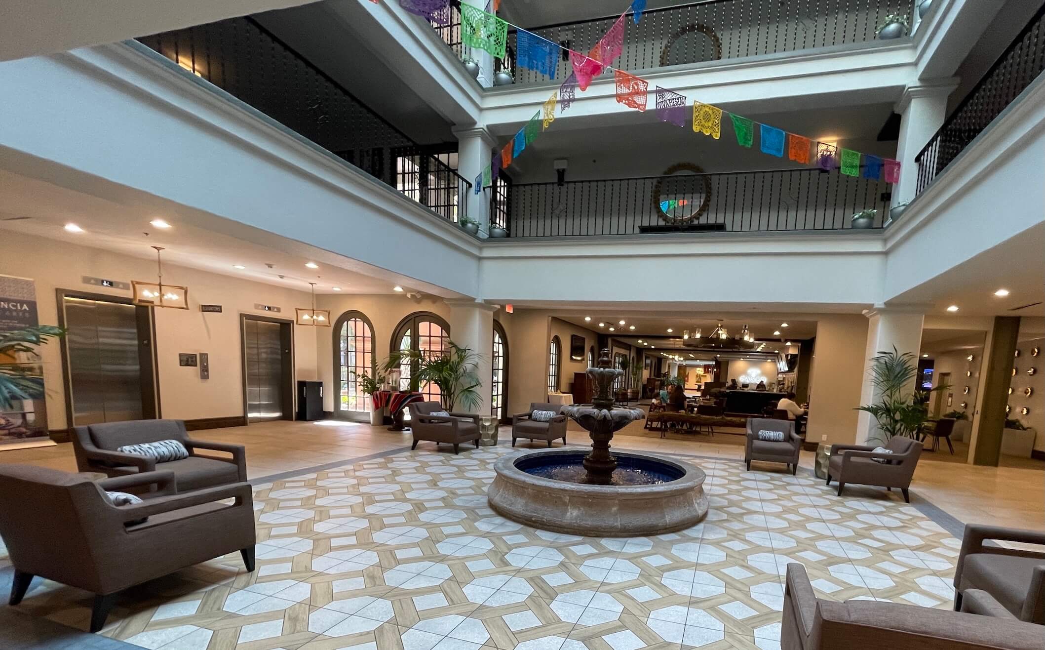 The open atrium lobby and central fountain area of the hotel, decorated with colorful hanging banners.