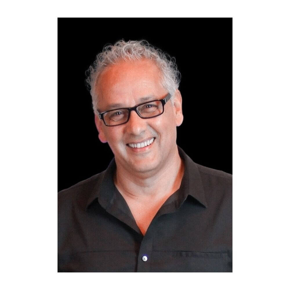 Option 1: Short & Direct (Recommended) Headshot of Robert Luna, a man with curly grey hair and black-rimmed glasses, smiling and wearing a black button-down shirt against a solid black background.