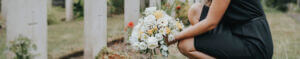 woman with flowers grieving loss at grave site