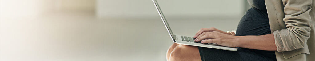 pregnant woman sitting on folding chair using laptop