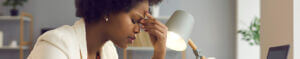 stressed woman with hand to forehead at office desk