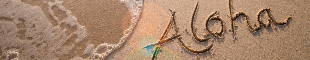 aloha written in the sand on a beach