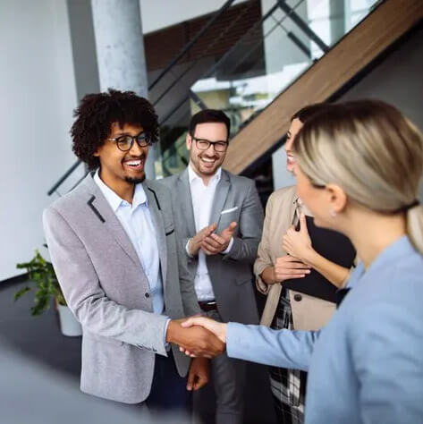 man shaking hands in a group of business people.