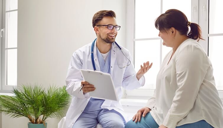 Portrait of fat overweight female patient in medical office listening to a friendly doctor holding report file with appointment and giving consultation a woman during medical examination in clinic.