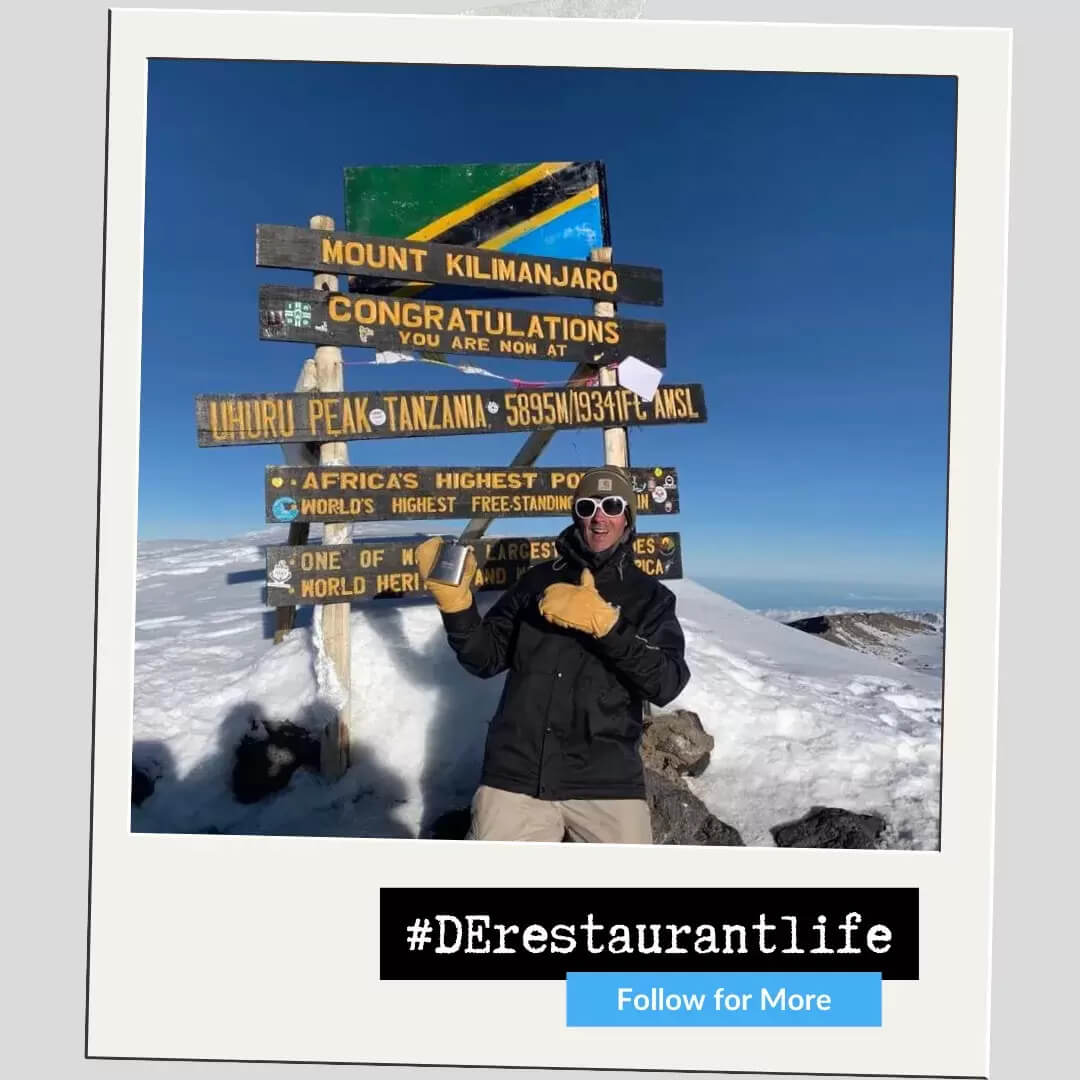 smiling in front of mount Kilimanjaro sign