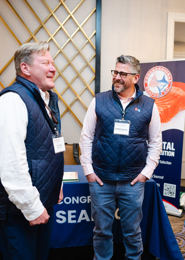 2 men laughing in front of booth