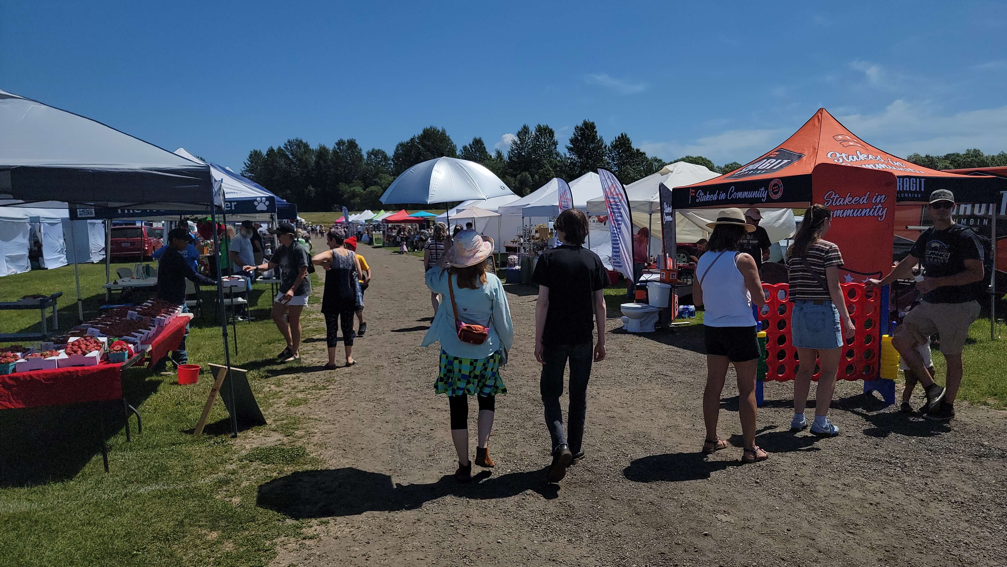 Visitors walk between vendor booths at the Berry Dairy Days Vendor Fair in Burlington, Washington.