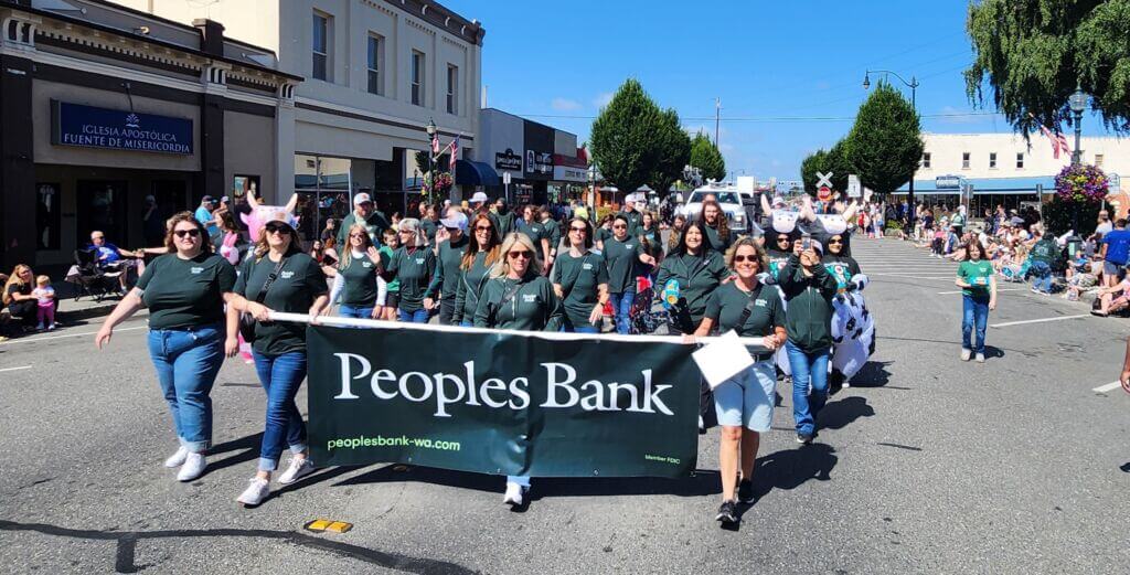 Peoples Bank parade group carrying their banner while walking in the Berry Dairy Days Grand Parade in downtown Burlington, Washington.