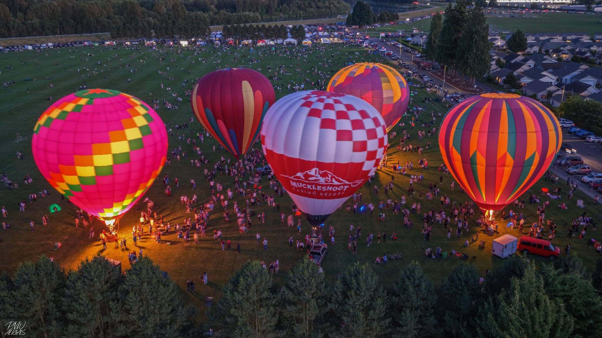 Aerial view of illuminated hot air balloons glowing on the ground during the Berry Dairy Days Hot Air Balloon Glow at Skagit River Park in Burlington, Washington.