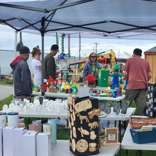 Shoppers browse handmade crafts, tumblers, décor, and gifts at vendor booths during the Burlington Artisan & Agricultural Market.