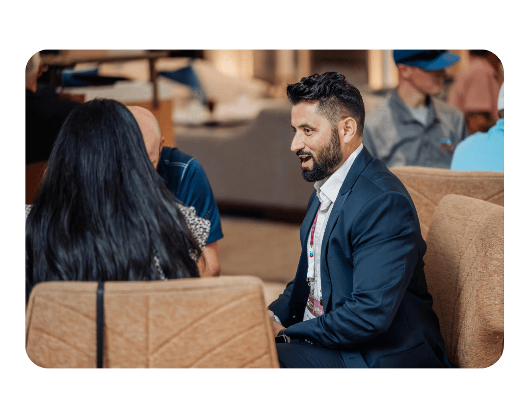 man in suits sits at a table talking to 2 others