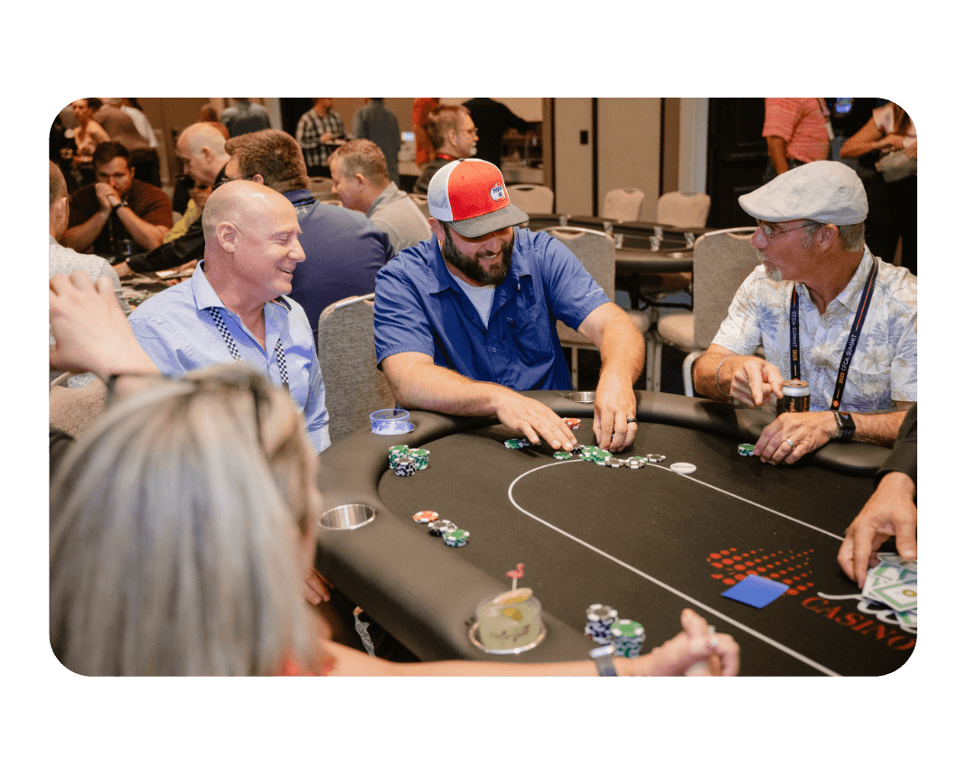 men sitting around a poker table. Man in the middle pulls poker chips closer to him.