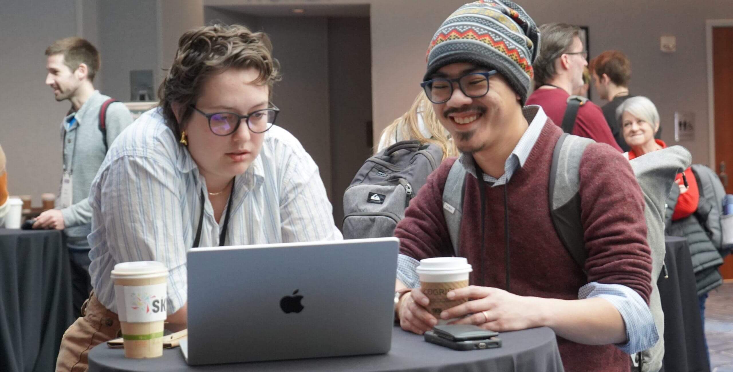 two people at NICAR conference standing by a tall table with an open laptop