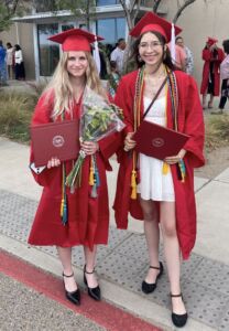 Lily Alexander (left) and Lauren Lifke (right) stand together wearing caps and gowns for their journalism school graduation in May 2025.