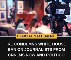 Official statement: IRE condemns white house ban on journalists from cnn, ms now and politico. Image shows a video camera in the foreground, points at a group of people in the background.
