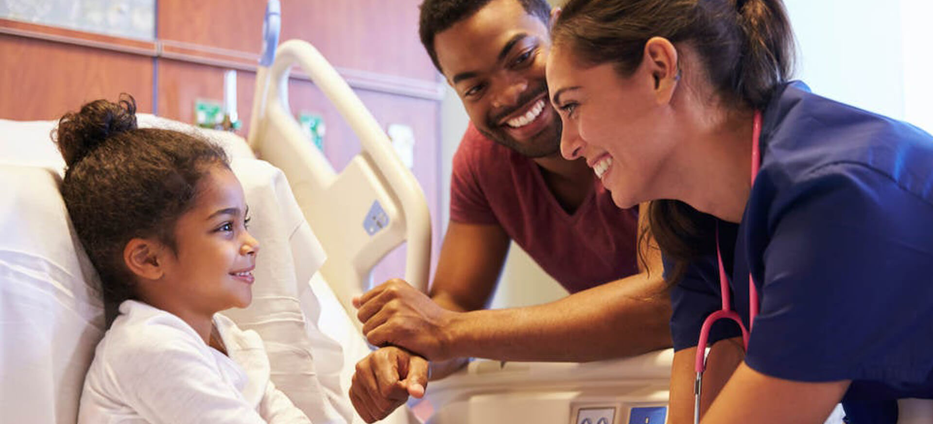 child in hospital bed laughing with nurse