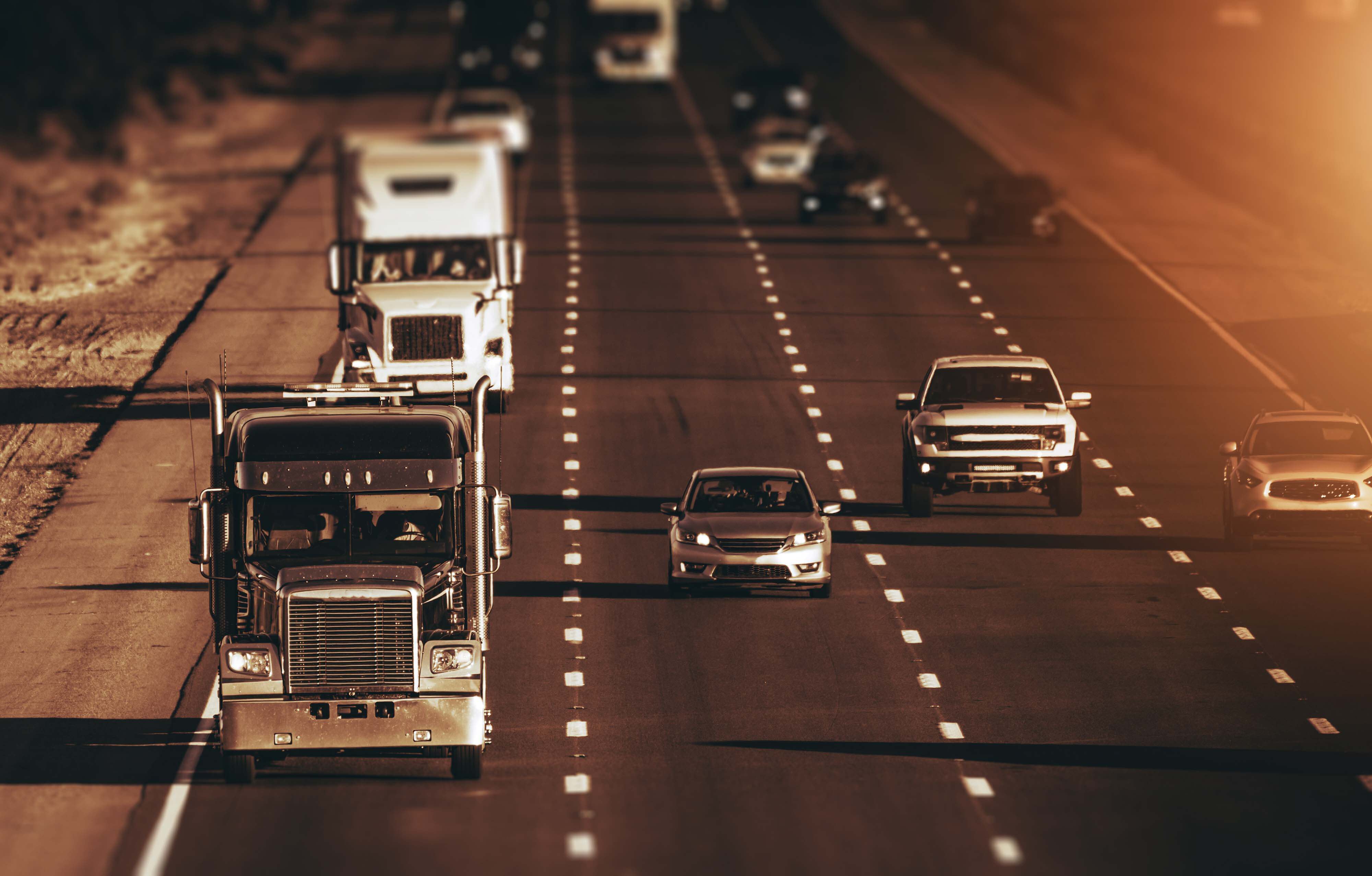 California Highway Traffic. Four Lanes One Direction Highway. Trucks and Cars on the Way. American Transportation Theme. Dark Sepia Color Grading.
