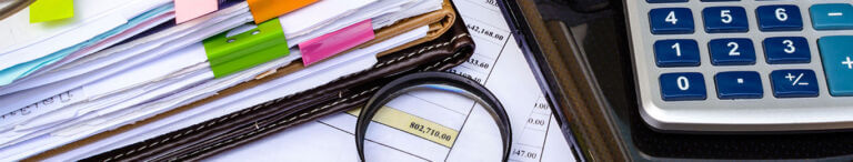 binder of documents with calculator and magnifying glass