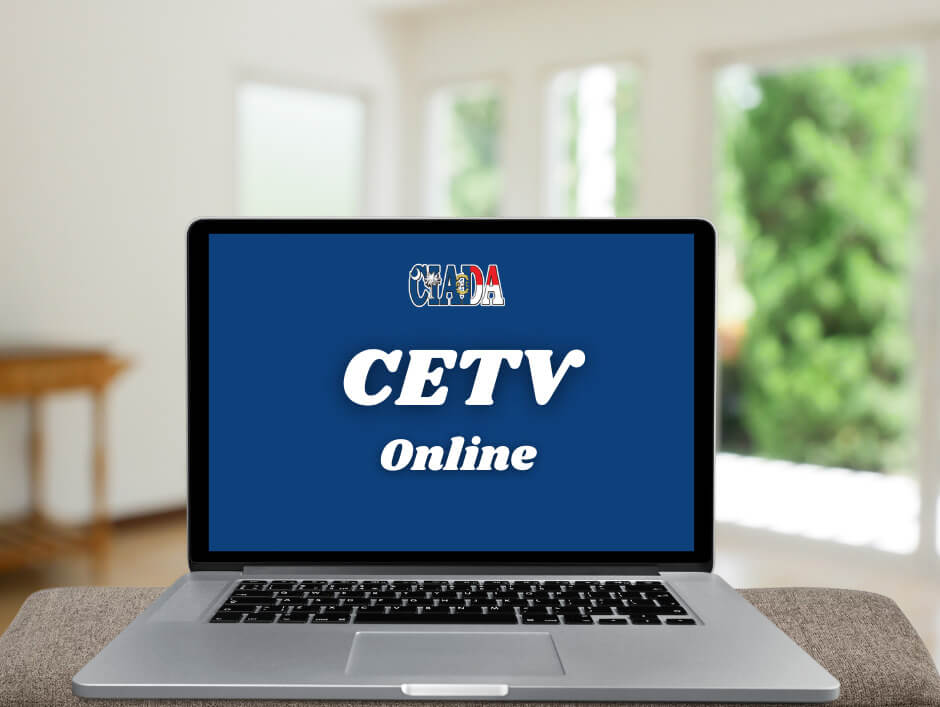 A laptop is open sitting on an ottoman. The screen reads as follows"CIADA CETV Online". A blurred background features what appears to be a living room.