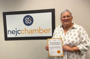 Cindy Beals from Santa Fe Waystation in front of NEJC Chamber sign