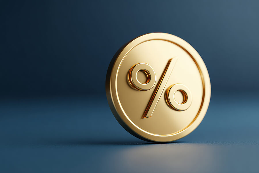 A gold coin with a percentage sign on it is tilted and spinning against a blue background