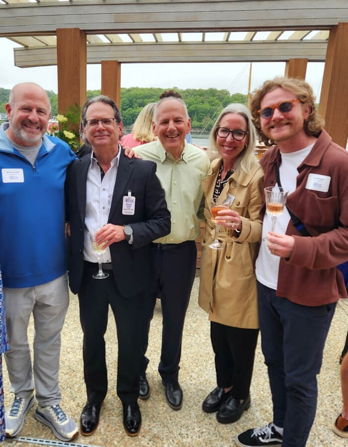 Five smiling people posing together at a networking or community event