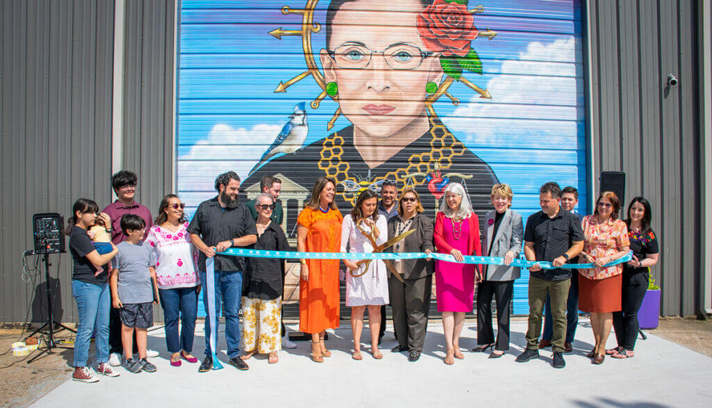 ribbon cutting in front of mural