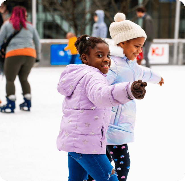 Girls ice skating with other skaters in the background