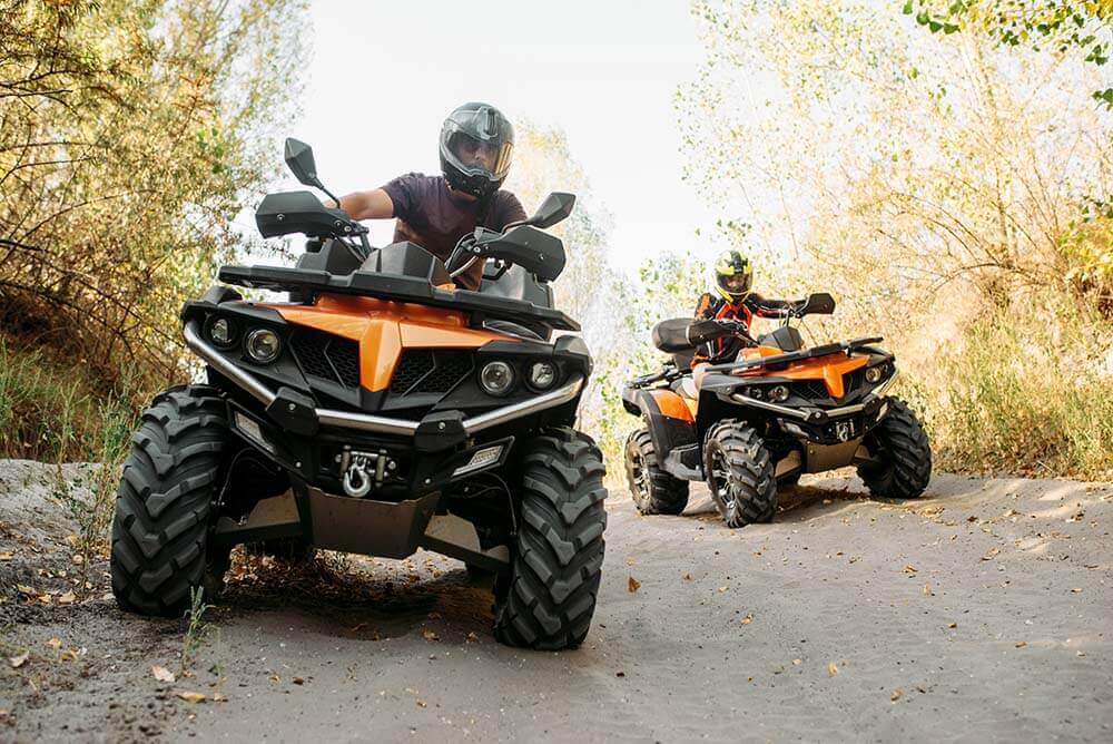 Two ATVs on wooded trail