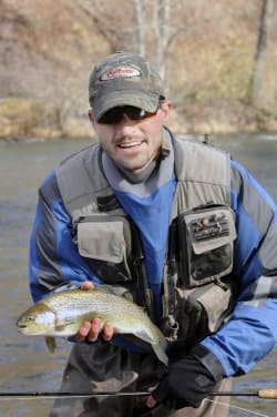 Man standing in stream holding trout he caught fly fishing