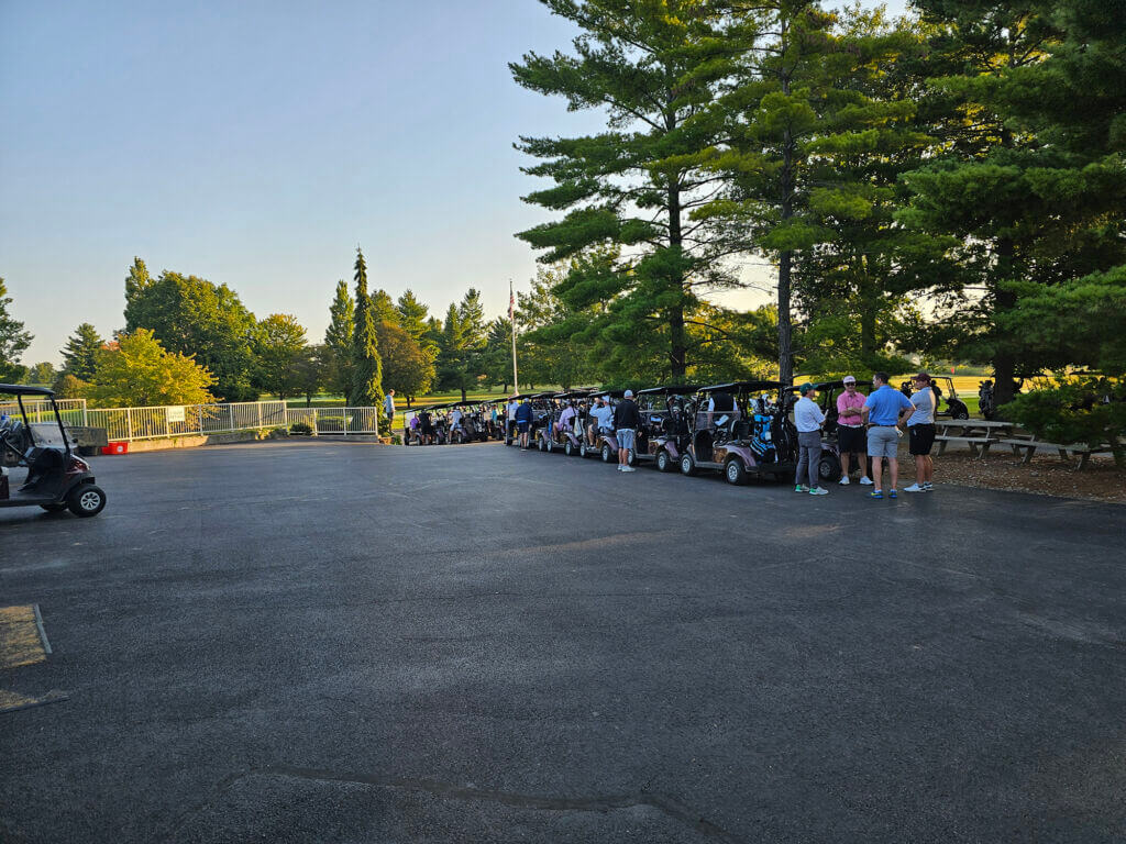 A wide view of golf carts and players assembled on the course
