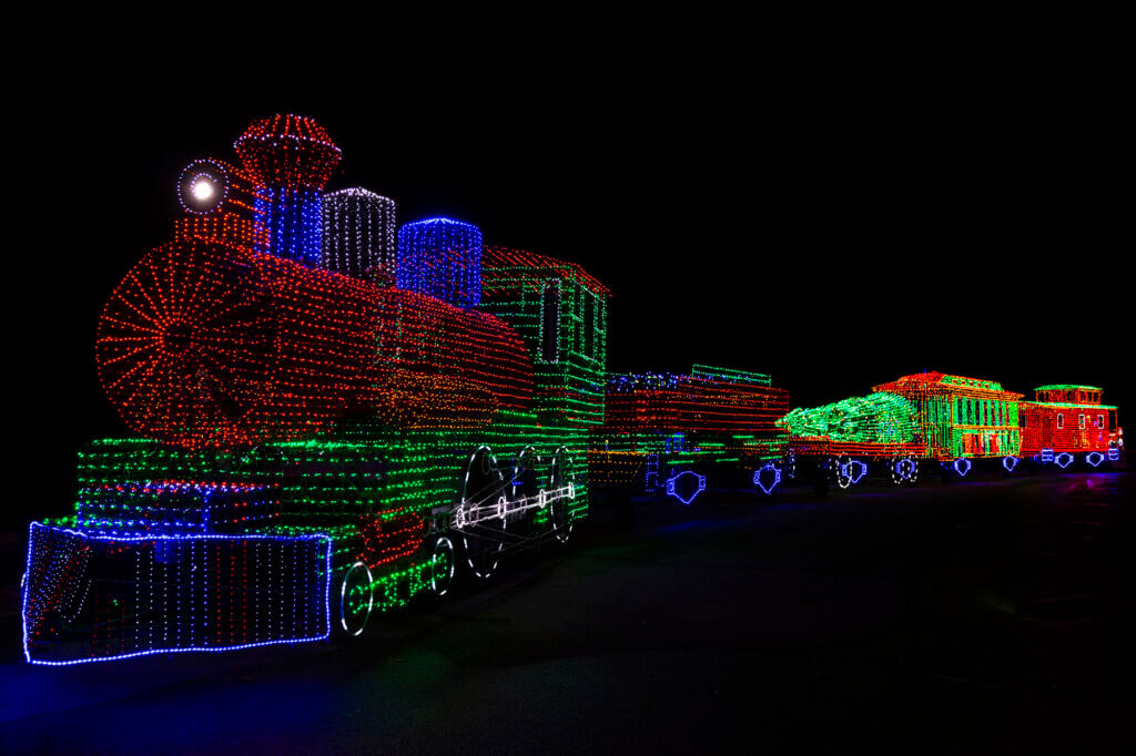A colorful illuminated train display in red, blue, and green at the Festival of Lights