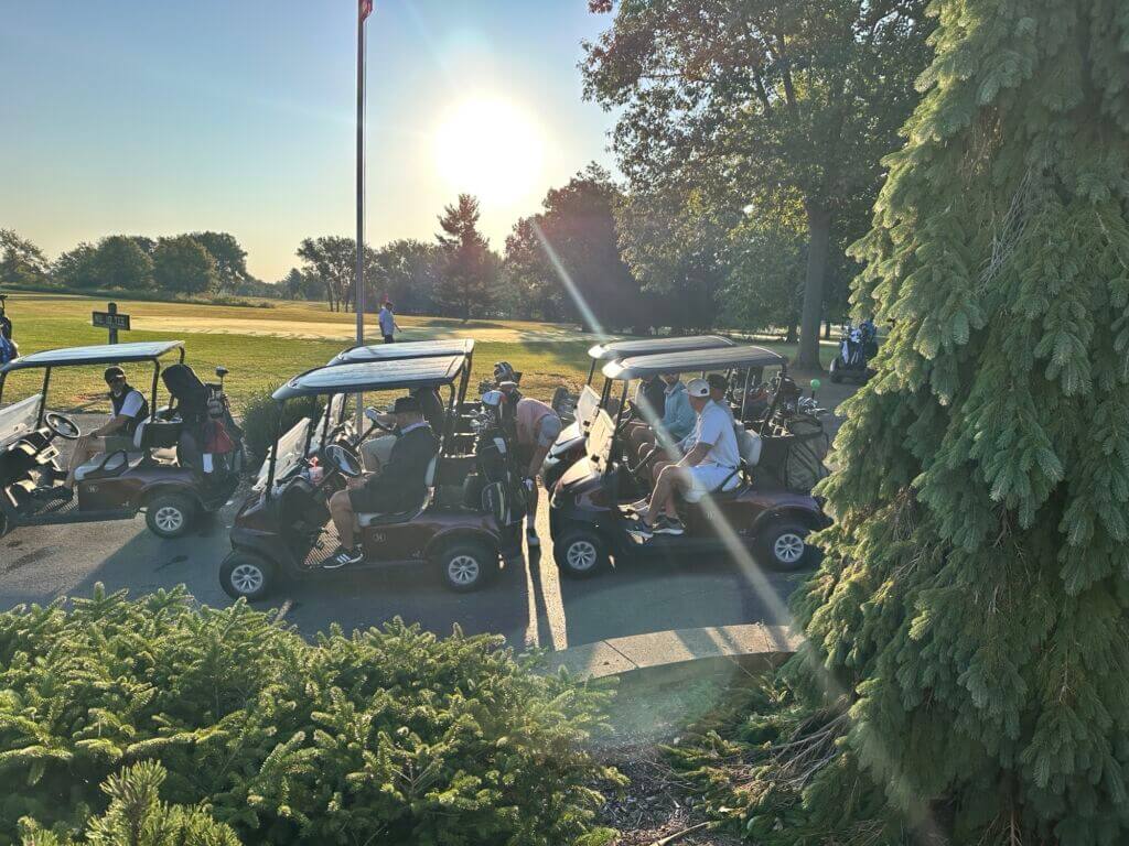 Golf carts parked near trees at sunset during the Golf Classic