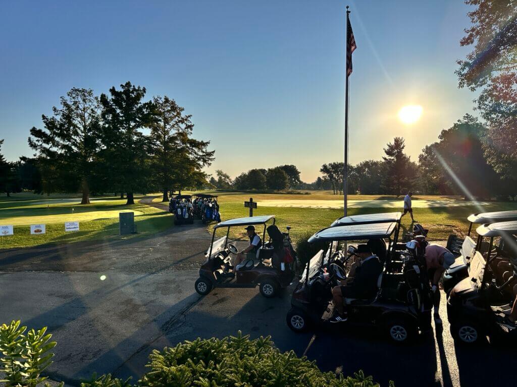 A line of golf carts travels along a cart path on the golf course