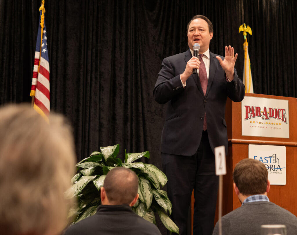 A speaker addresses the crowd at a podium during the Annual Dinner, with an American flag in the background