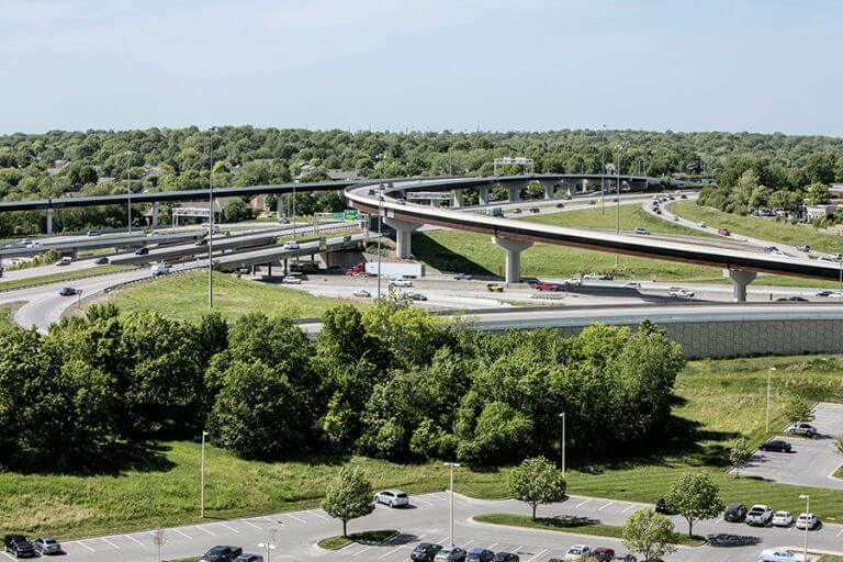 Flyover-768x512 Aerial view of a highway interchange surrounded by green trees and suburban development