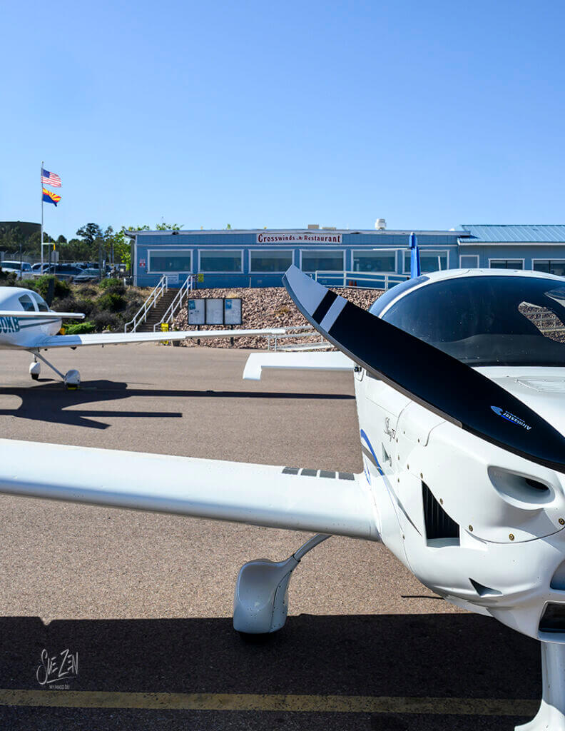 Small white aircraft parked on tarmac at a regional airport