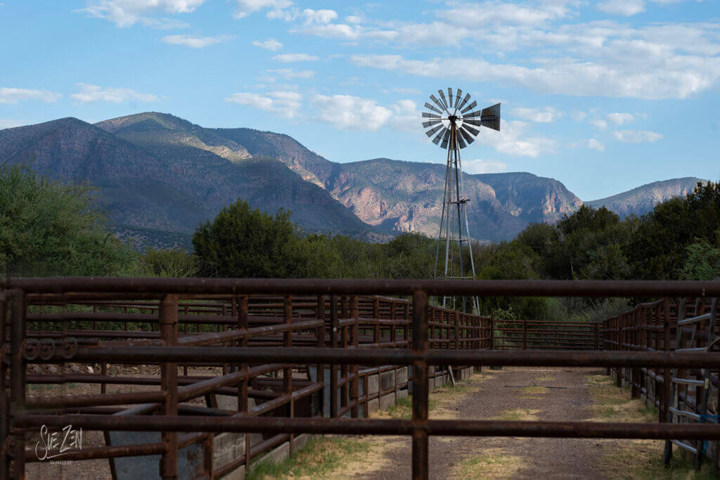 Vintage windmill beside a wooden bridge with mountain views