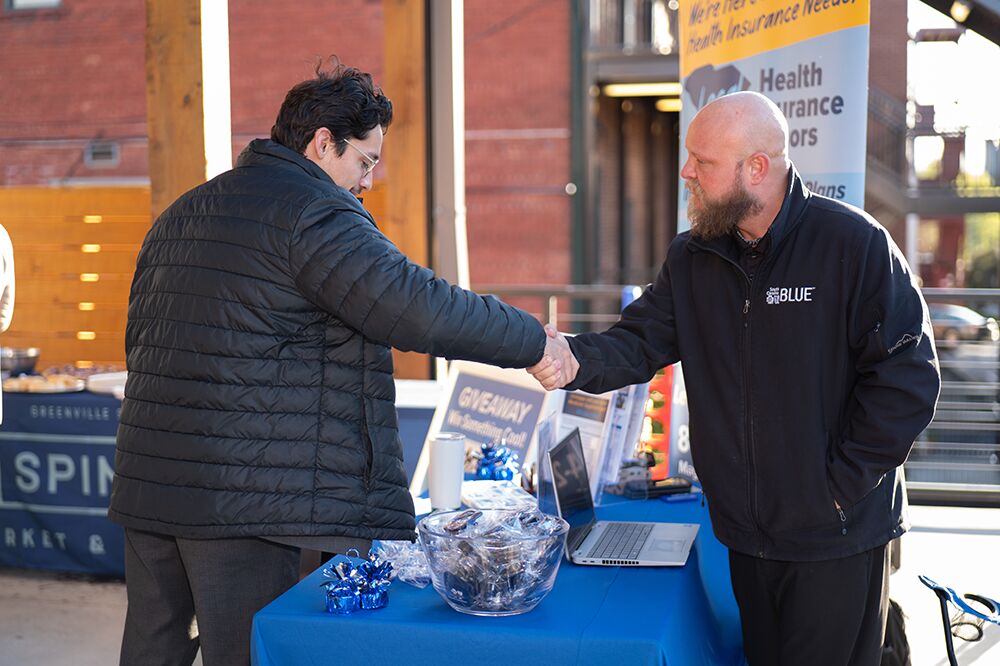 Attendees shaking hands at a sponsor table